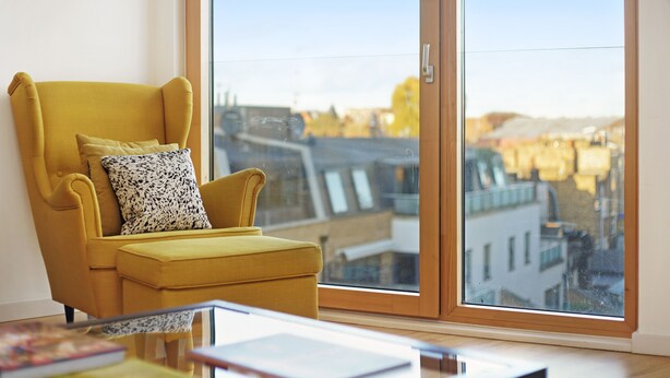 A yellow armchair with a patterned pillow next to a large window with a city view. - 1 Bedroom Stylish Apartment near Regents Park FREE WIFI & AIRCON by City Stay Aparts London (London)