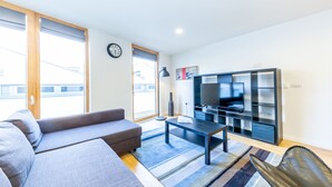 A modern living room with a sofa, a coffee table, a TV, and a bookshelf. - 1 Bedroom Stylish Apartment near Regents Park FREE WIFI & AIRCON by City Stay Aparts London (London)