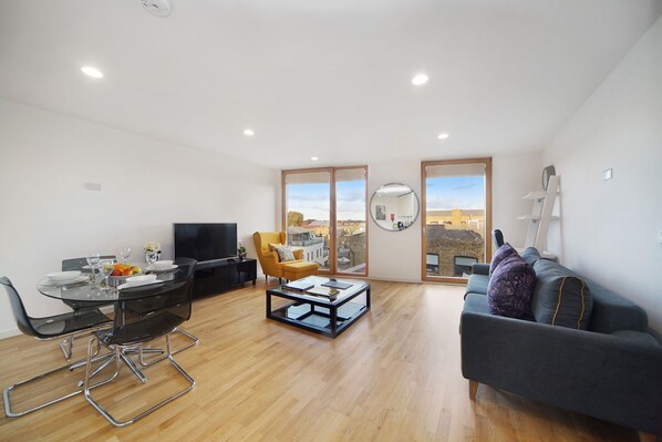 A modern living room with a dining area, a sofa, a coffee table, and a TV.
