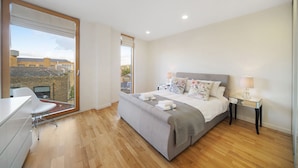 A modern bedroom with a large bed, a desk, and a chair. - 1 Bedroom Stylish Apartment near Regents Park FREE WIFI & AIRCON by City Stay Aparts London (London)
