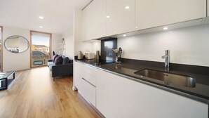 A modern kitchen with a black countertop, stainless steel sink, and white cabinets. - 1 Bedroom Stylish Apartment near Regents Park FREE WIFI & AIRCON by City Stay Aparts London (London)