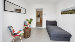 A modern living room with a sofa, a colorful chair, a small wooden table, and a large mirror. - Finding My Palace in Tooting (London)