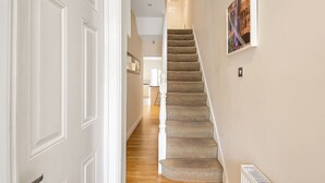 A hallway with a carpeted staircase, white doors, and a framed picture on the wall. - Finding My Palace in Tooting (London)