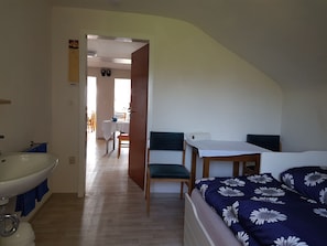 Cozy retreat with a single bed, wooden table, and kitchenette area.