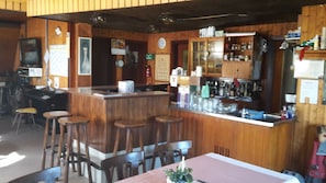 Enjoy a casual dining experience at this rustic bar, featuring a wooden counter and stools, framed pictures, and comfortable seating.