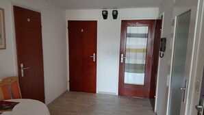 A hotel room with two wooden doors, a small table with a white tablecloth, and a wooden floor. - Gasthof Waldeck (Engstingen)