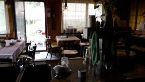A restaurant interior with a bar area, tables, chairs, and a window with a view. - Gasthof Waldeck (Engstingen)