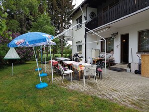 An outdoor patio area with a table and chairs, a blue umbrella, and a garden setting. - Gasthof Waldeck (Engstingen)