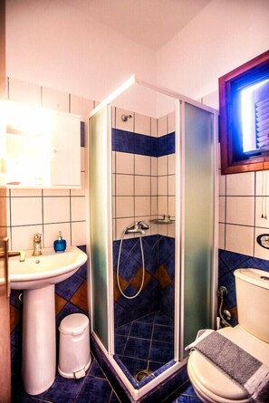 Ein Badezimmer mit Dusche, Waschbecken, Toilette und Spiegel.