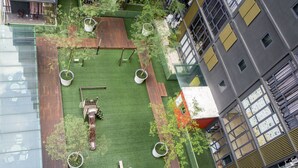 Vue aérienne d’un jardin sur le toit, avec des plantes en pot, des terrasses en bois et un espace aménagé pour s’asseoir.