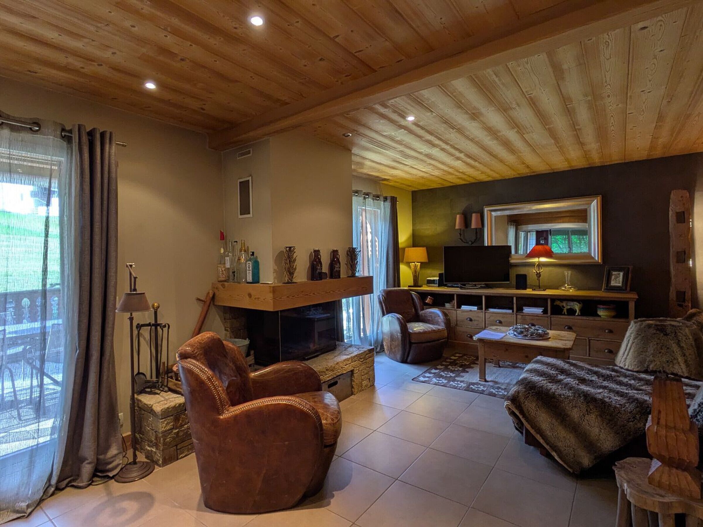 A cozy living room with a fireplace, leather armchair, and a television.