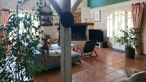 Un salón amplio con chimenea, asientos cómodos y ventanas grandes.