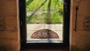 Puerta con vista a un jardín cubierto de césped y árboles.