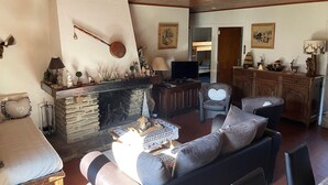 Een gezellige woonkamer met een open haard, een televisie en een eethoek met houten meubels.