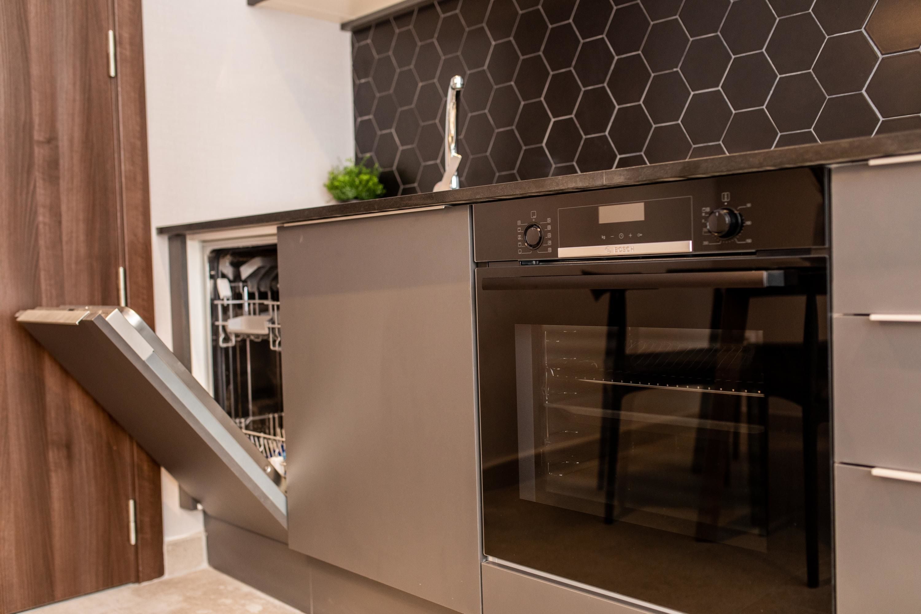 A modern kitchen with a dishwasher, oven, and a built-in sink.