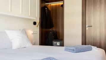 A hotel room with a bed, a wardrobe, and a desk with a telephone.