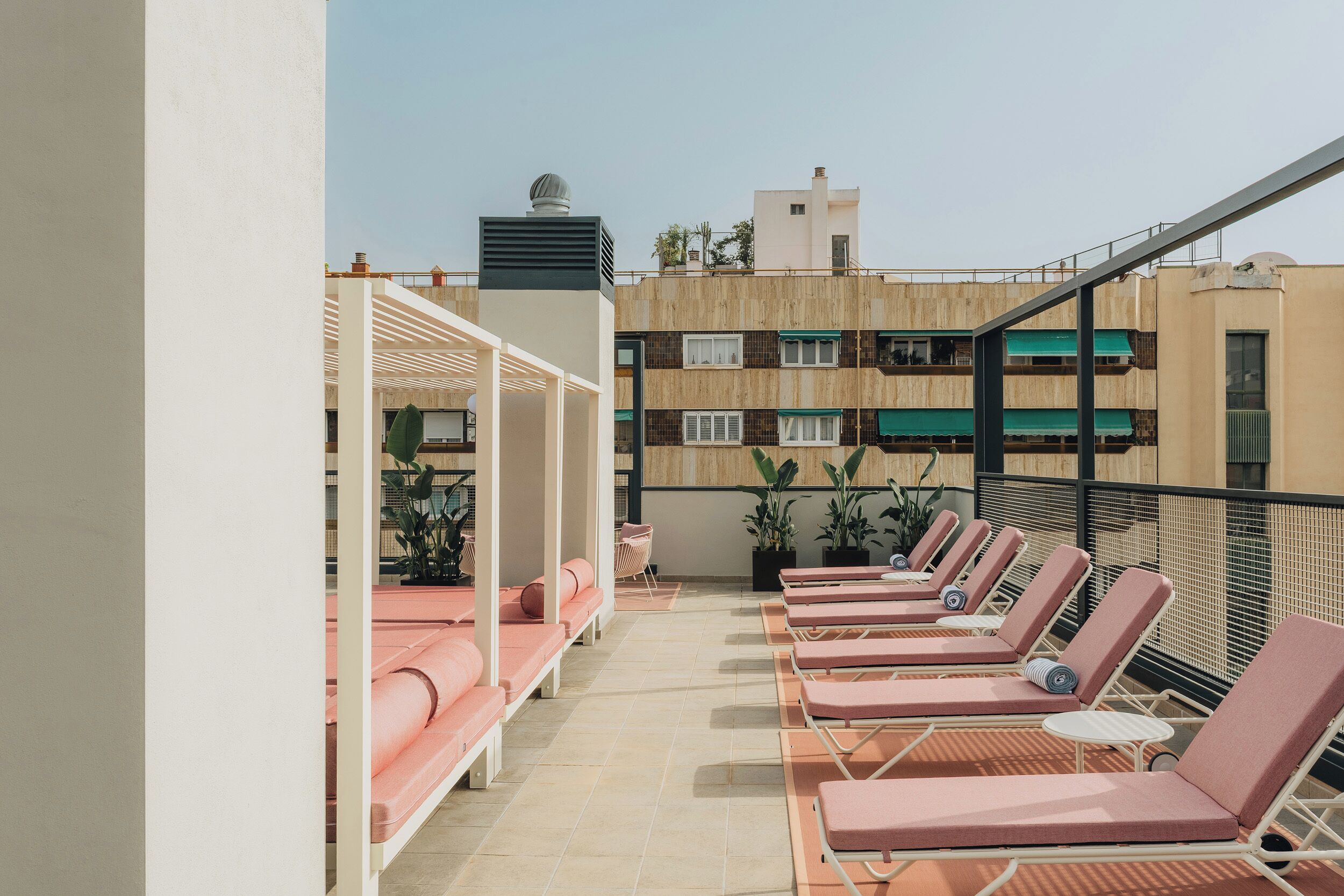 A rooftop terrace with sun loungers and a pergola.