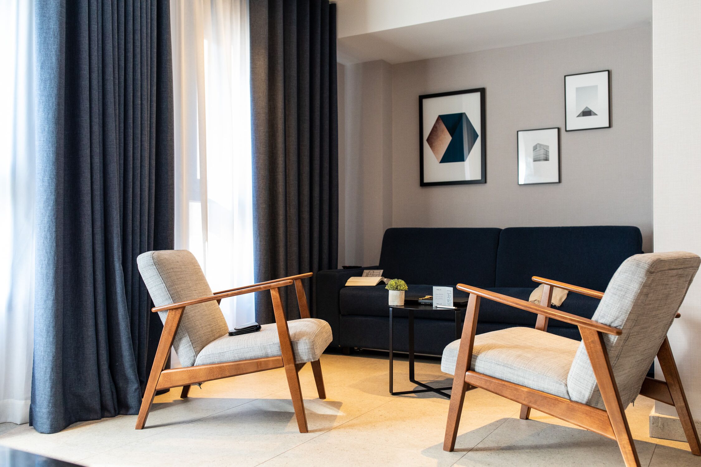 Un salon moderne avec deux fauteuils, un canapé foncé et une table basse.