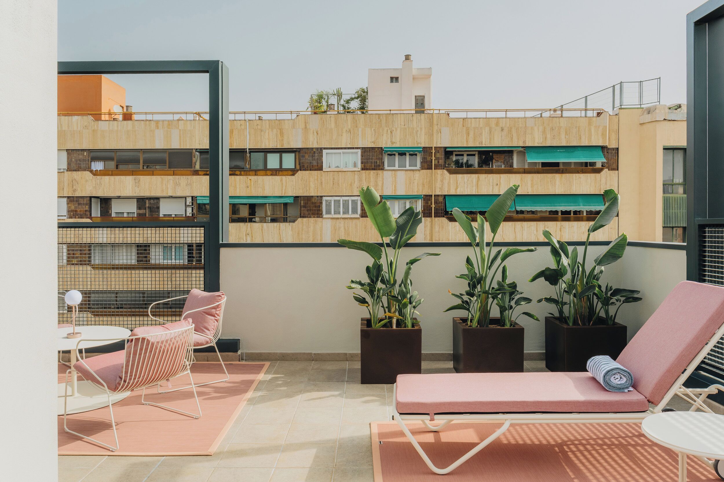 Un balcone con una poltrona da relax, un tavolino e piante in vaso.