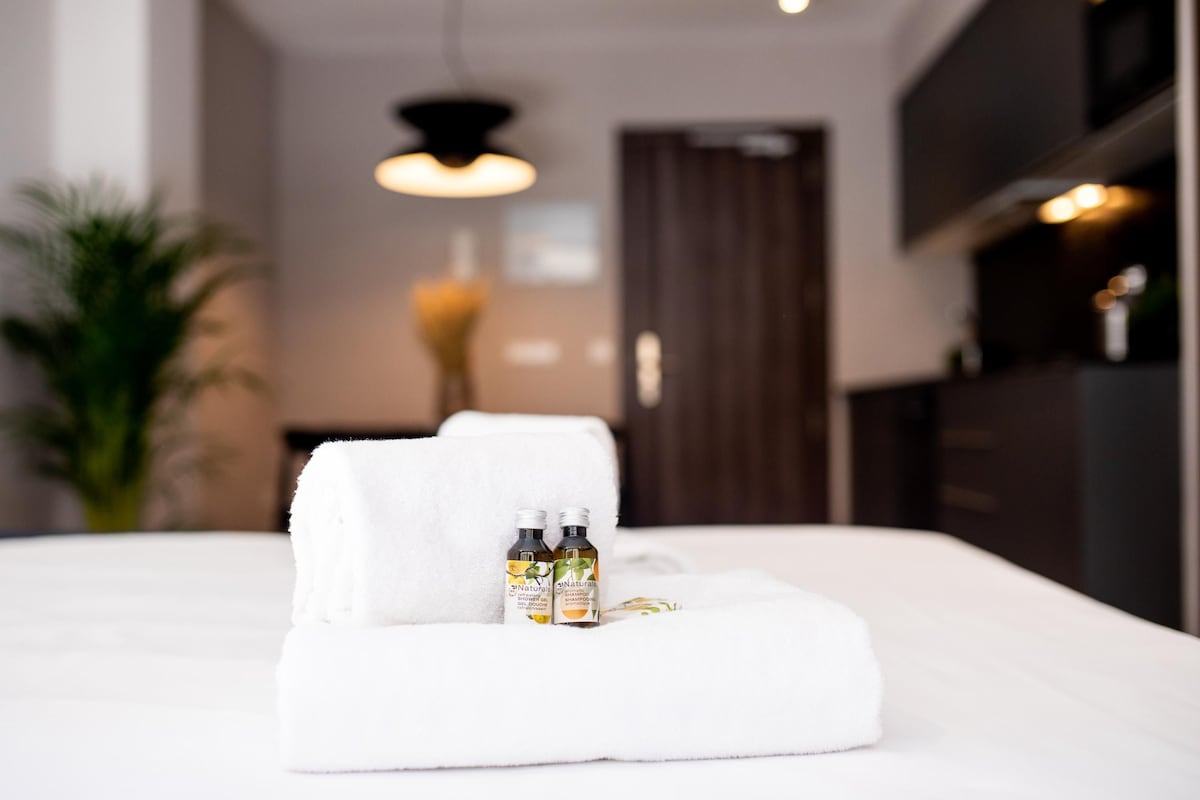 A neatly made bed with a white towel and two bottles of lotion on it.