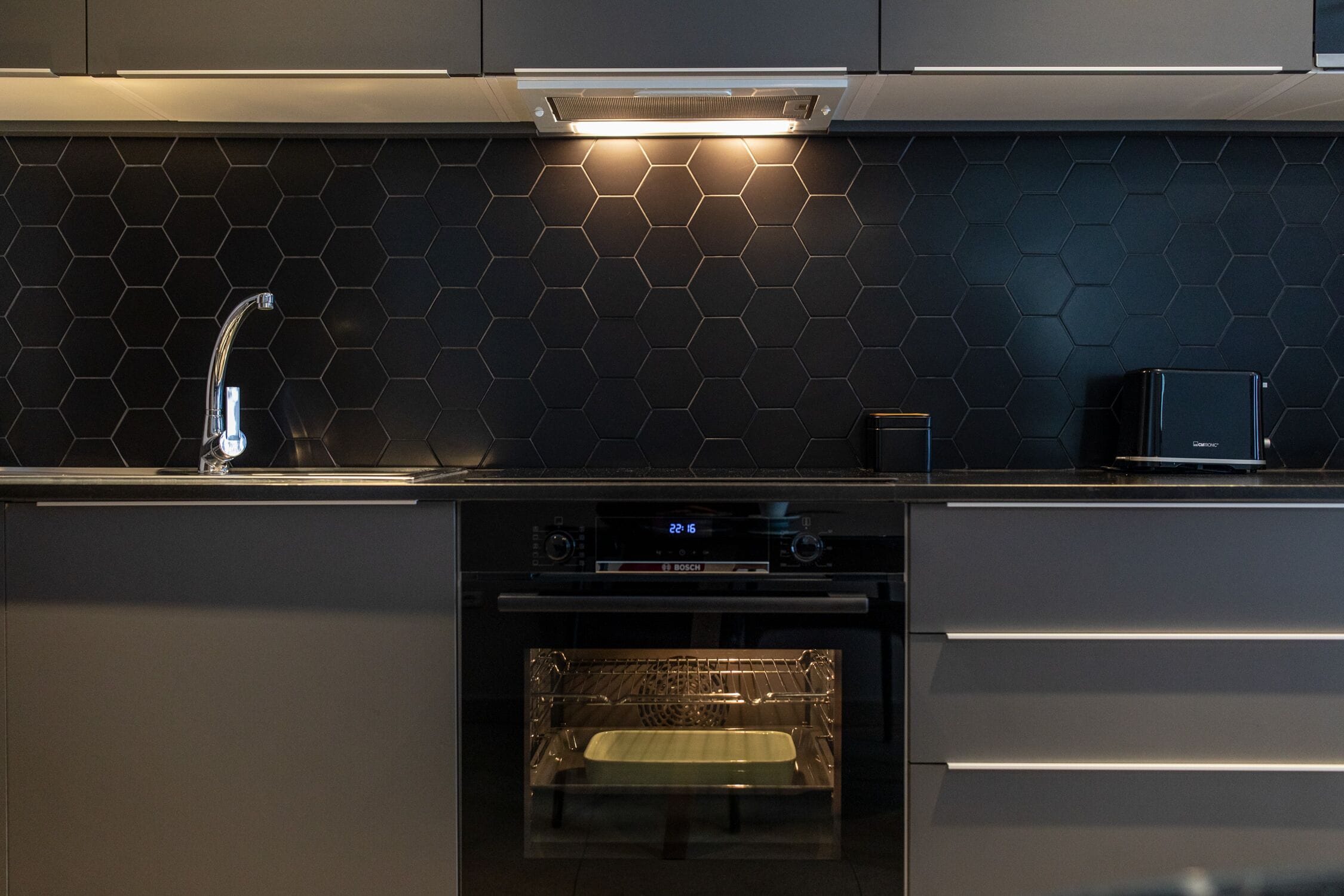 A modern kitchen with a Bosch oven, a built-in microwave, and a stainless steel sink.
