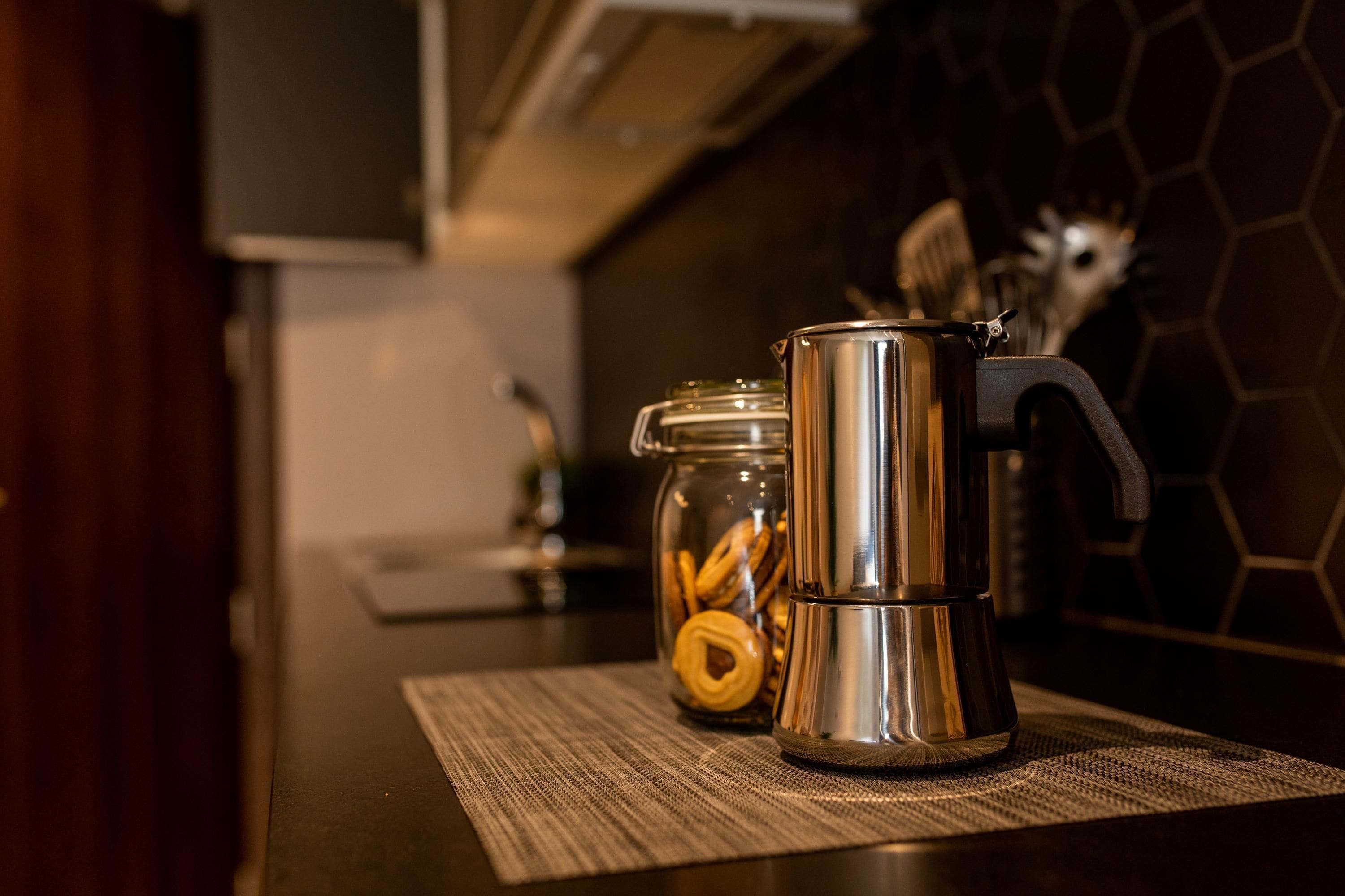 Un comptoir de cuisine avec une machine à café en acier inoxydable et un bocal en verre rempli de biscuits.