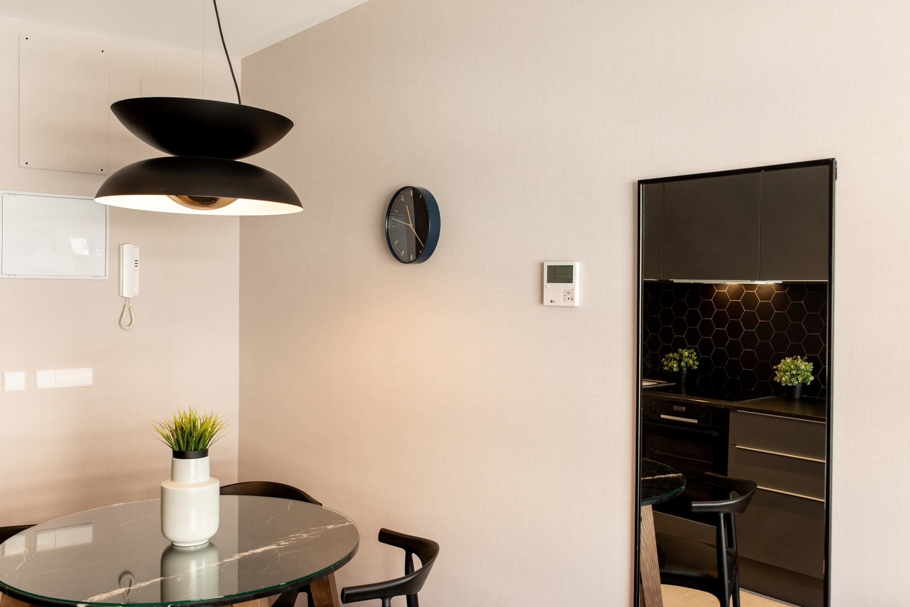 Una cocina moderna con un salpicadero negro, una mesa de comedor redonda con sillas y un reloj de pared.