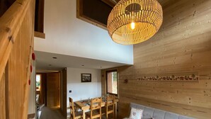 Een houten interieur met een eethoek, een bank en een hanglamp.