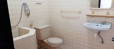 A small, tiled bathroom with a toilet, a sink, and a shower.