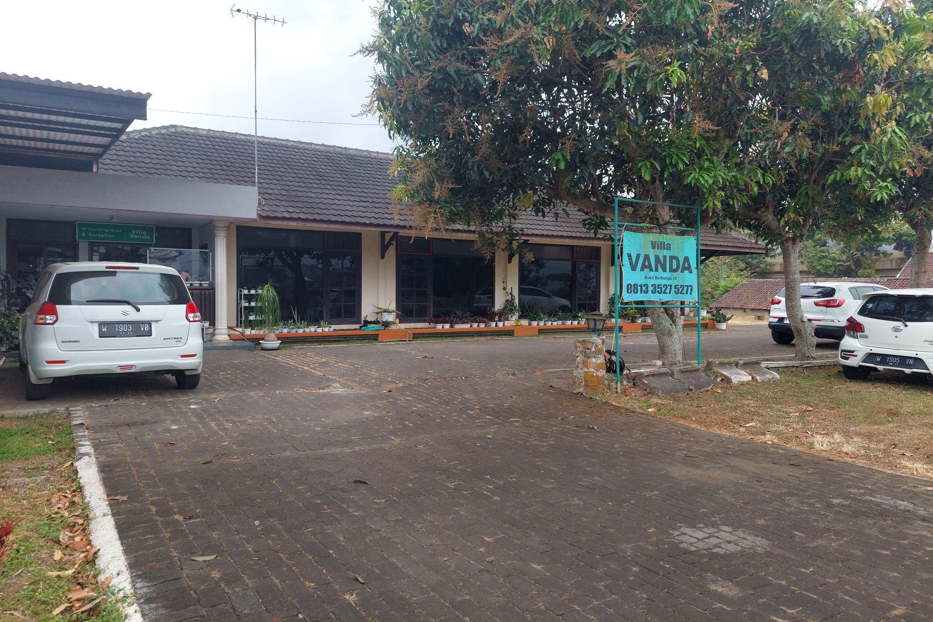 A building with a sign reading "Vanda" and a parking area with cars.