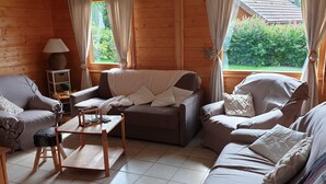 Een knus blokhut interieur met een houten vloer, twee banken, een salontafel en een lamp.