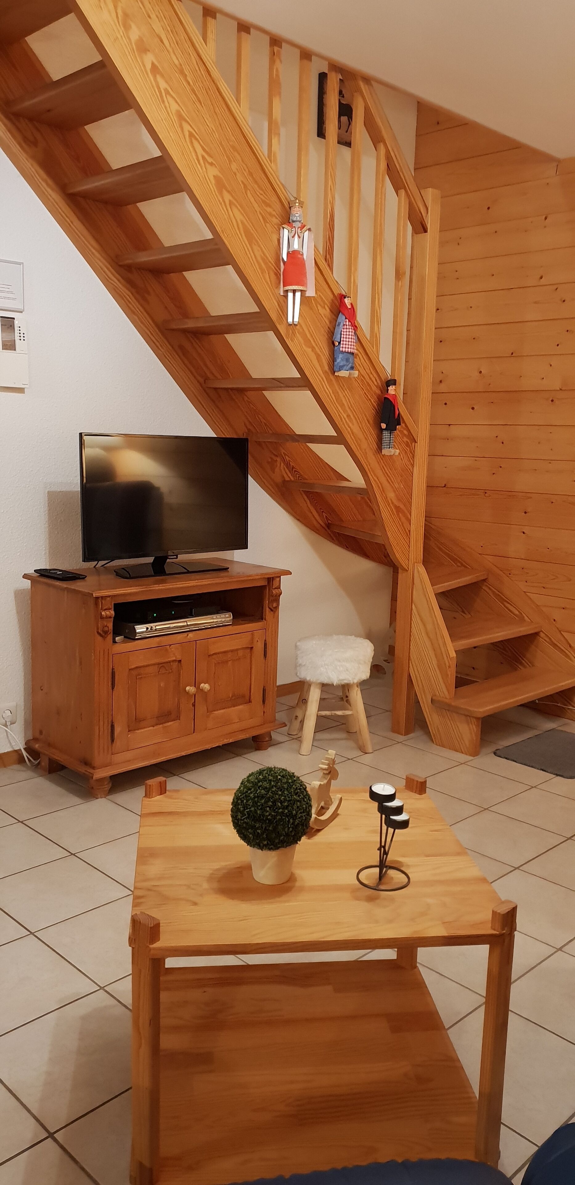 Een houten trap met een tv-kast en een kleine tafel met een plant en decoratie.