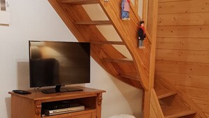 Een houten trap met een tv-kast en een kleine tafel met een plant en decoratie.