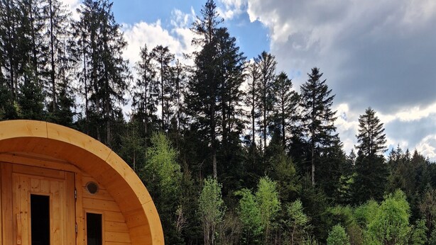 Een hoek met een bubbelbad, twee loungesteunen en een houten chaletstructuur.