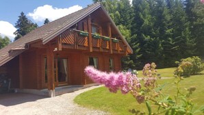 Een houten chalet met schuin dak, een veranda en een oprit van grind.