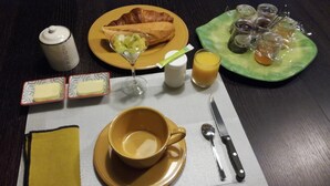 A breakfast table with croissant, fruit, juice, butter, and a cup of coffee. - Chambre Rose Blanche (Le Lude)