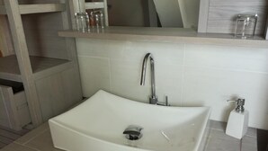 A bathroom with a white sink, a mirror above it, and a shelf with jars. - Chambre Rose Blanche (Le Lude)