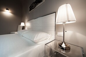 A hotel room with a bed, a nightstand, a lamp, and a wall-mounted light fixture. - Arco' Suite B&B (Trani)