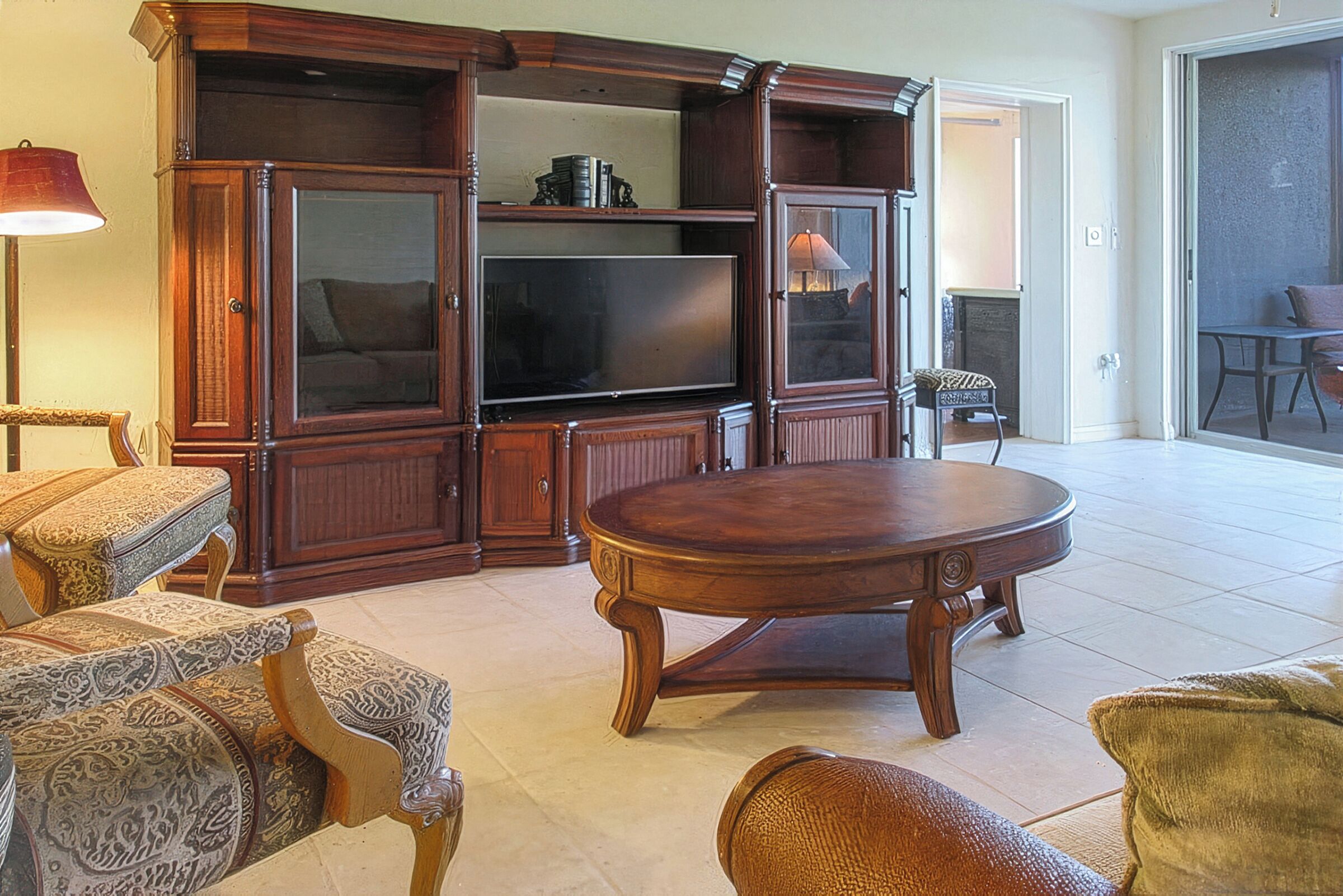 A living room with a large wooden entertainment center, a flat-screen TV, and a round coffee table.