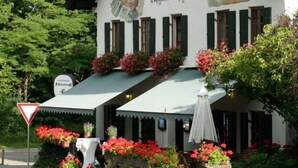 Een klassiek gebouw met een schuin dak, meerdere ramen en een bord waarop een restaurant wordt aangegeven.