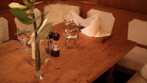 Een houten tafel met een bloemenvaas, zout- en pepervaatjes, een glas en een hertenbeeldje.