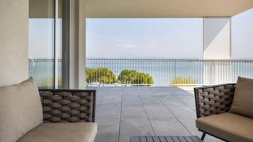 A balcony with two sofas and a table, overlooking a body of water and greenery.