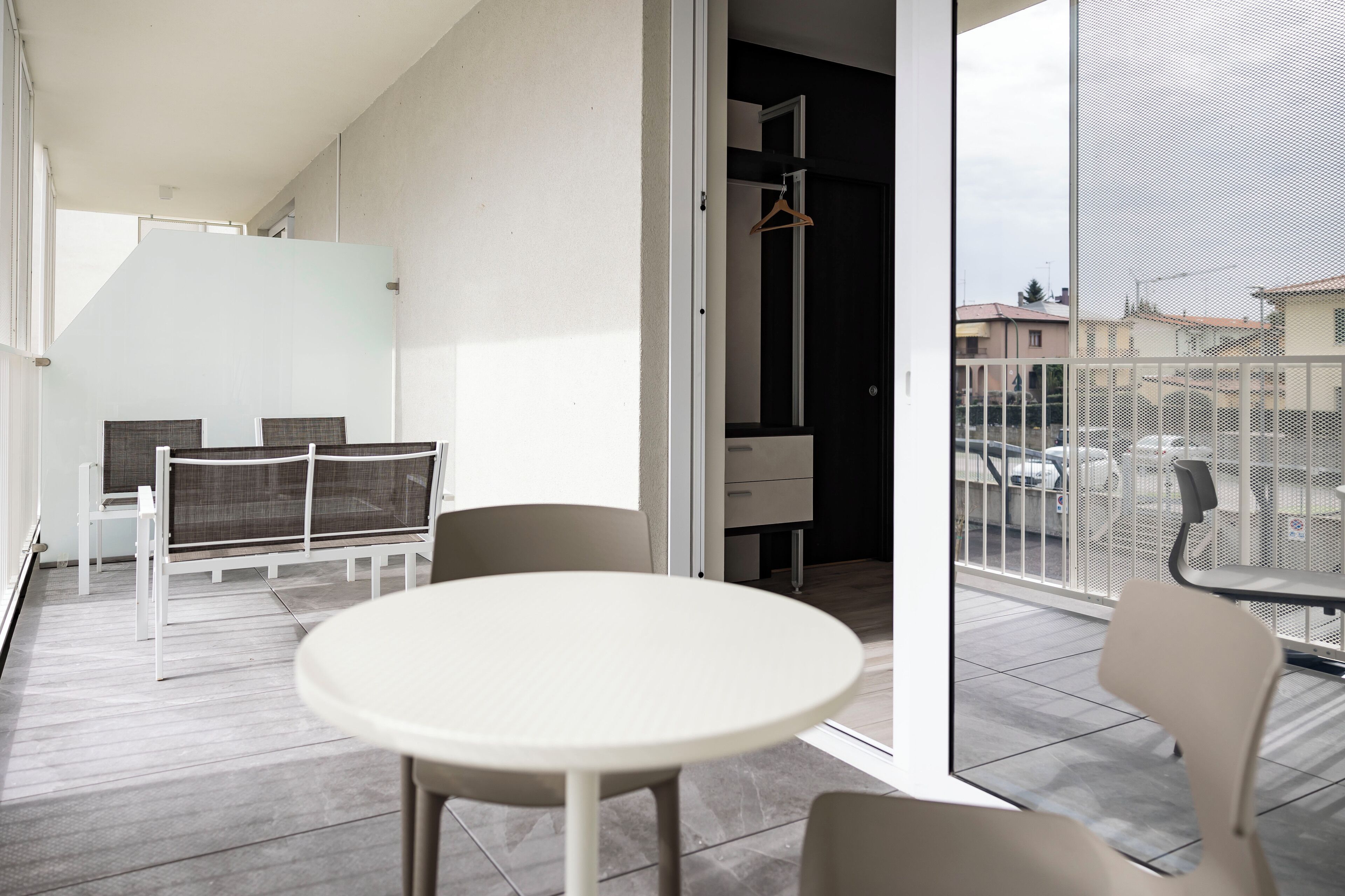 Ein Balkon mit rundem Tisch und Stühlen, einem Hängesessel und Blick auf die Straße.