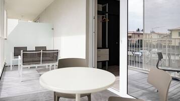 Ein Balkon mit rundem Tisch und Stühlen, einem Hängesessel und Blick auf die Straße.