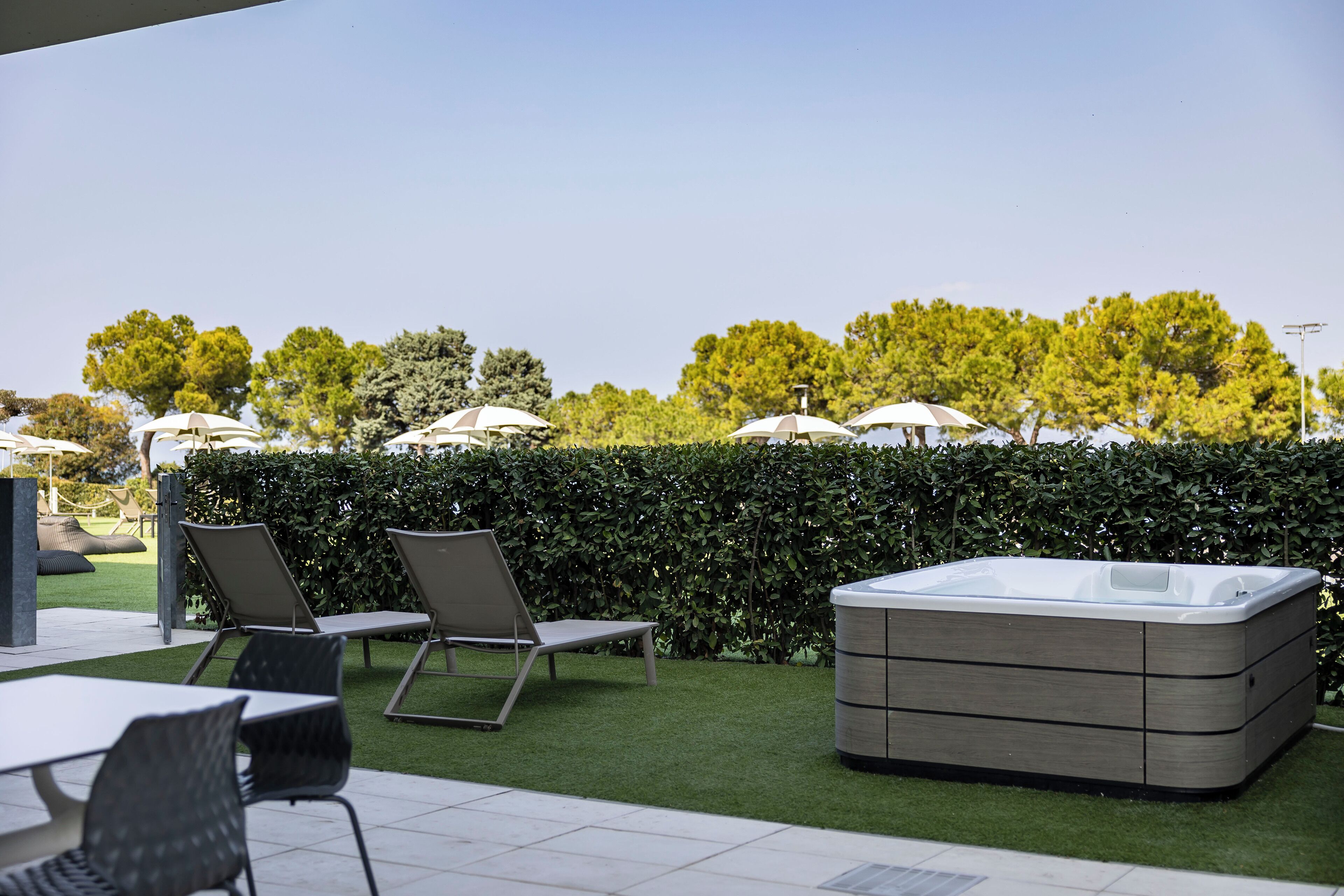 Un espacio al aire libre con un jacuzzi, sillones de descanso y sombrillas.