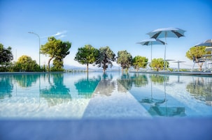 Una piscina al aire libre, sombrillas, sillones reclinables de piscina