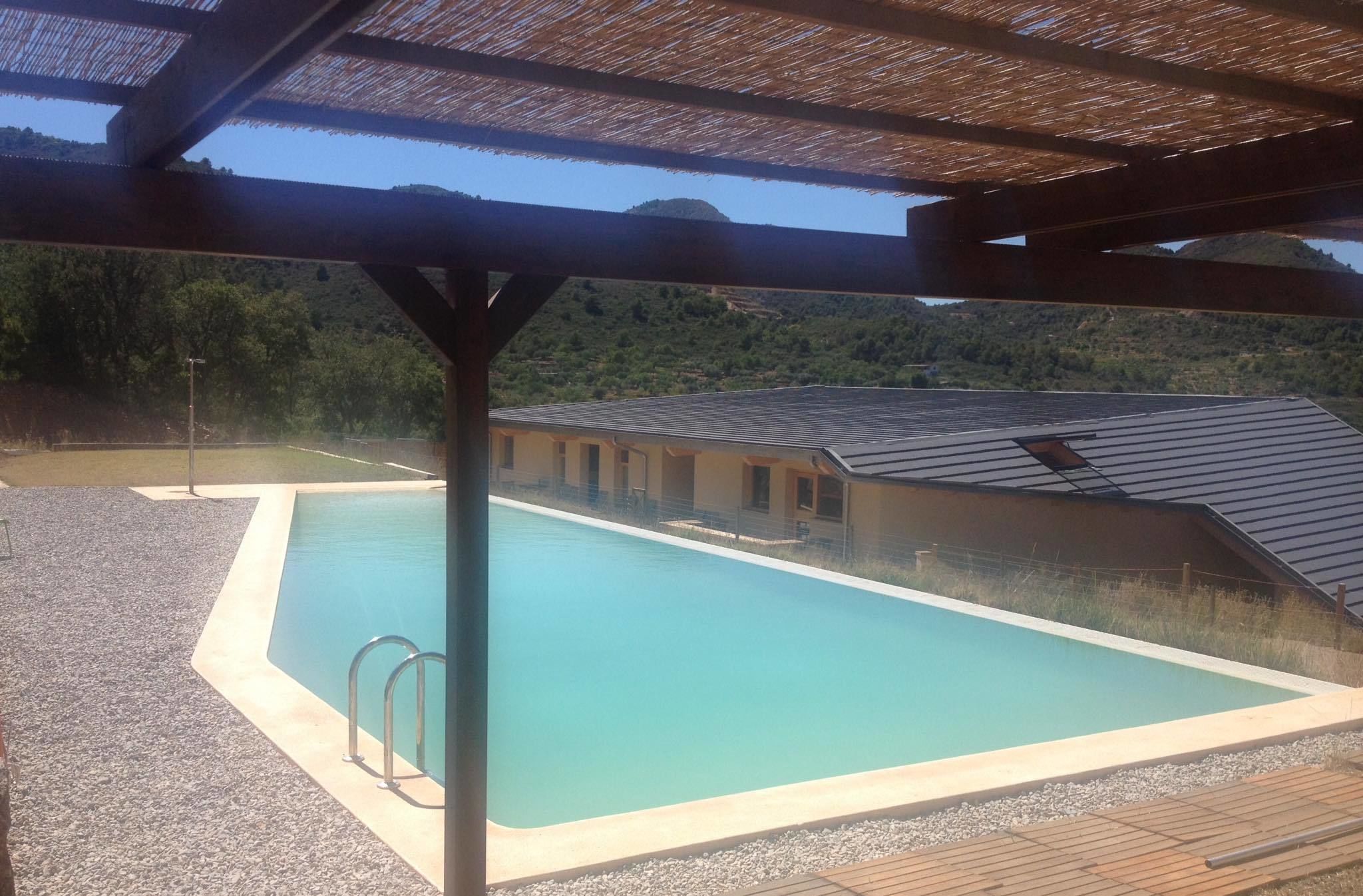 A swimming pool with a wooden deck and a covered area with a metal roof.