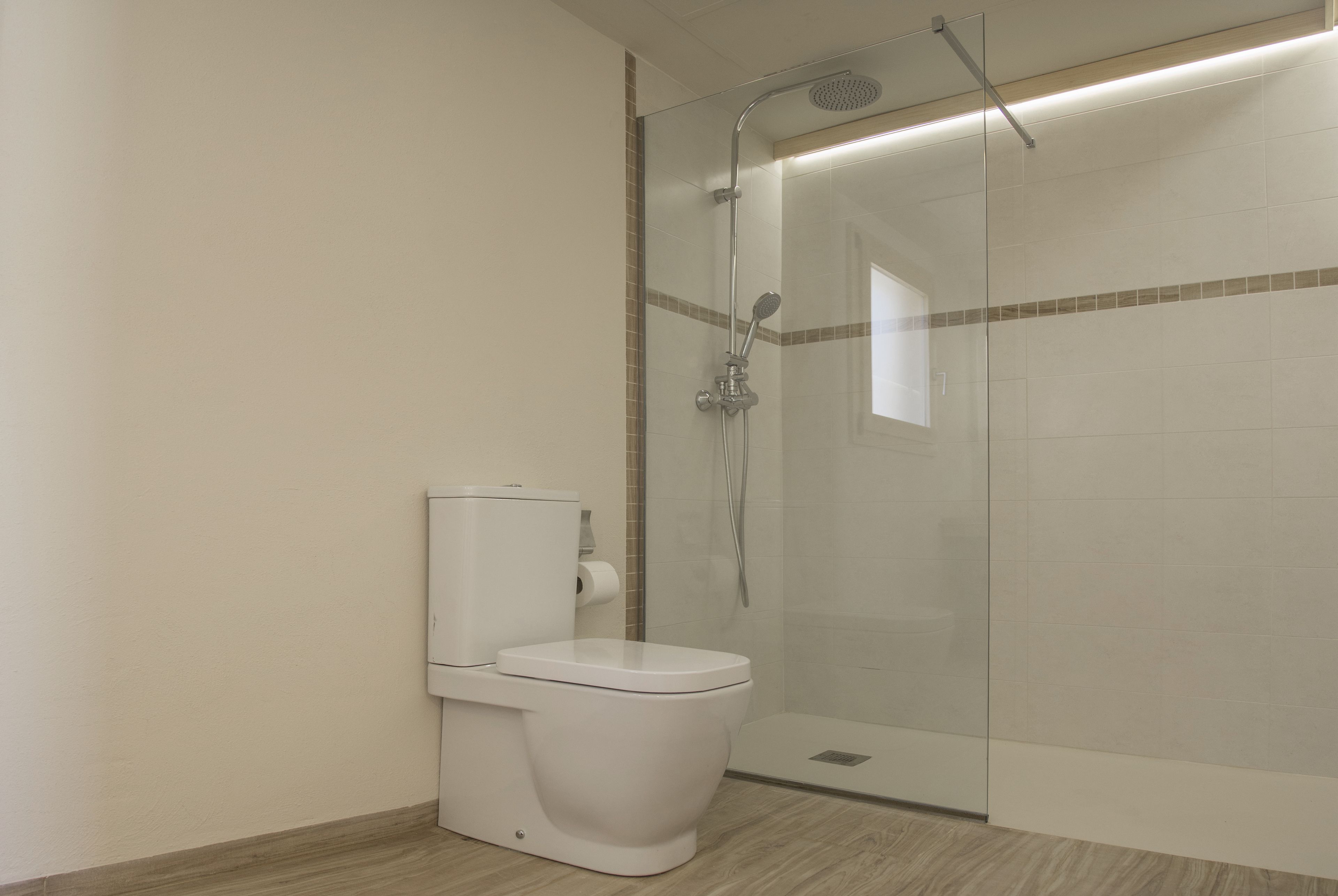 Un baño moderno con ducha de vidrio, inodoro blanco y suelo de baldosas.
