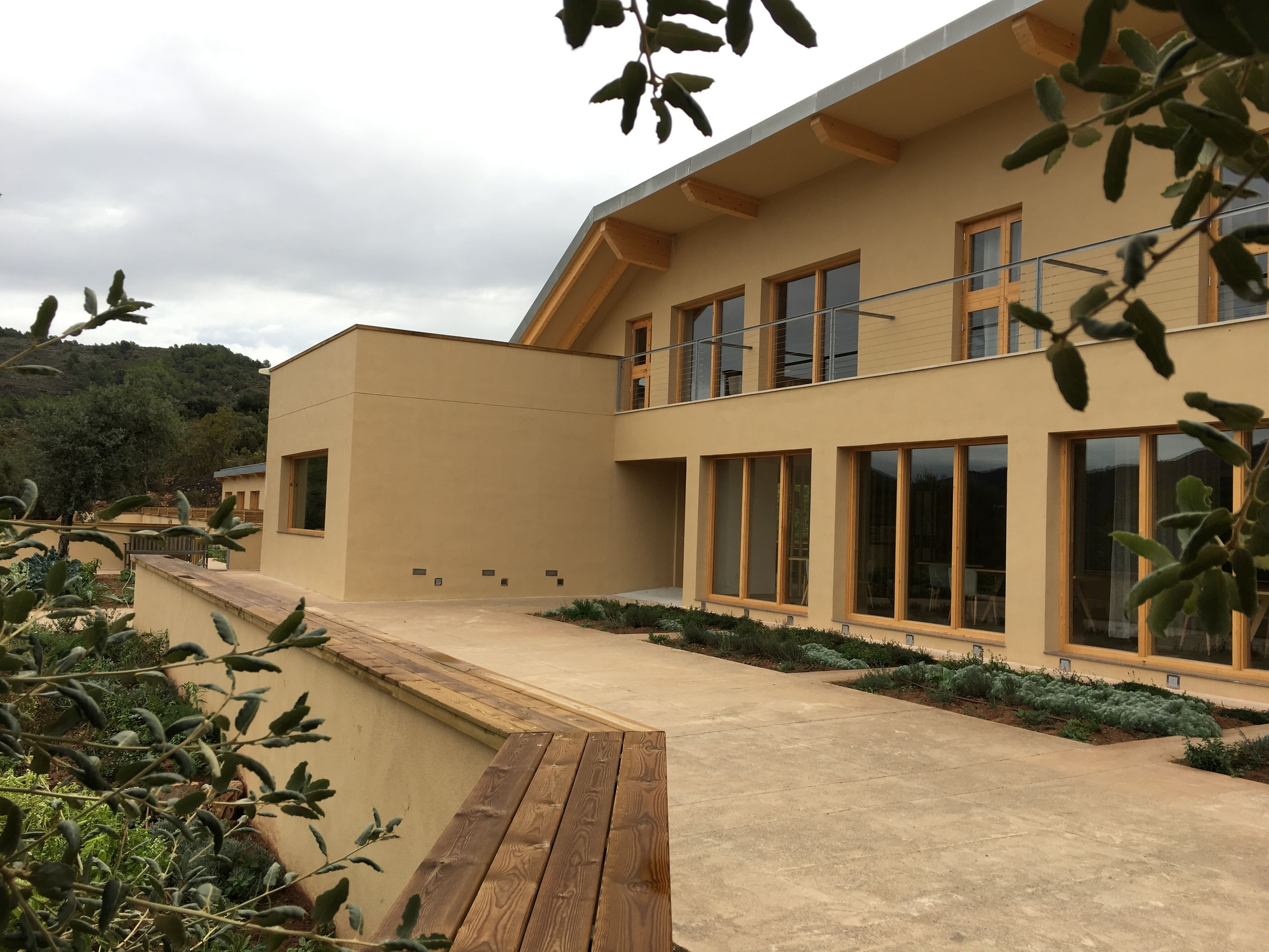 A modern building with large windows, a flat roof, and a wooden deck.
