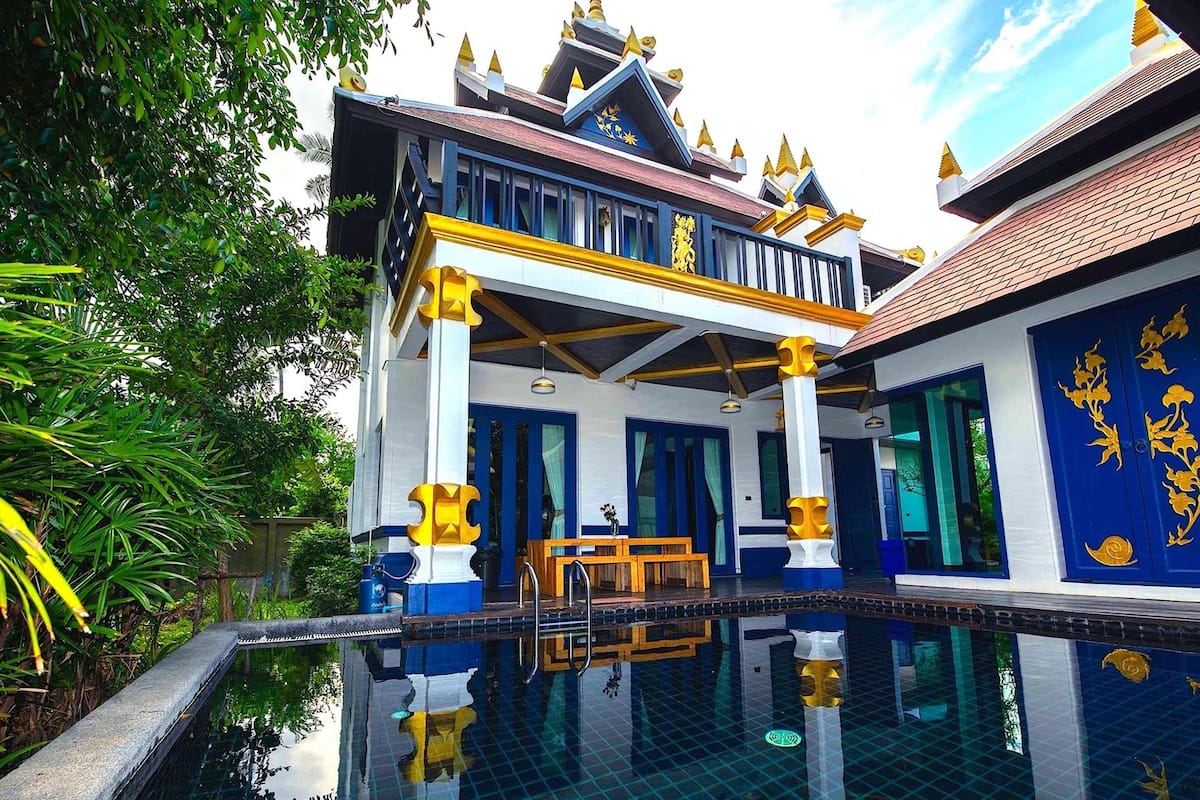 Un bâtiment traditionnel thaïlandais avec un bassin décoratif devant.